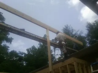 Carpenter setting a ridge beam over a new addition frame — Ice Dam Removal by Roofing Brothers in Perley