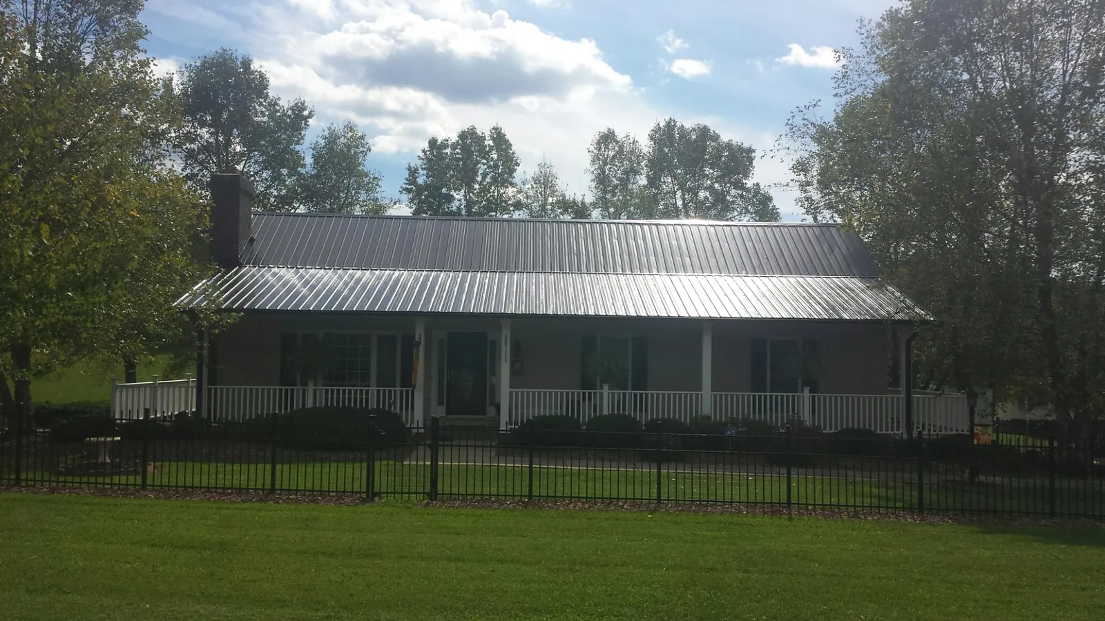 Gray metal roof on a brick ranch with a full width front porch — Gutter Guard Installation work by our crew in Perley