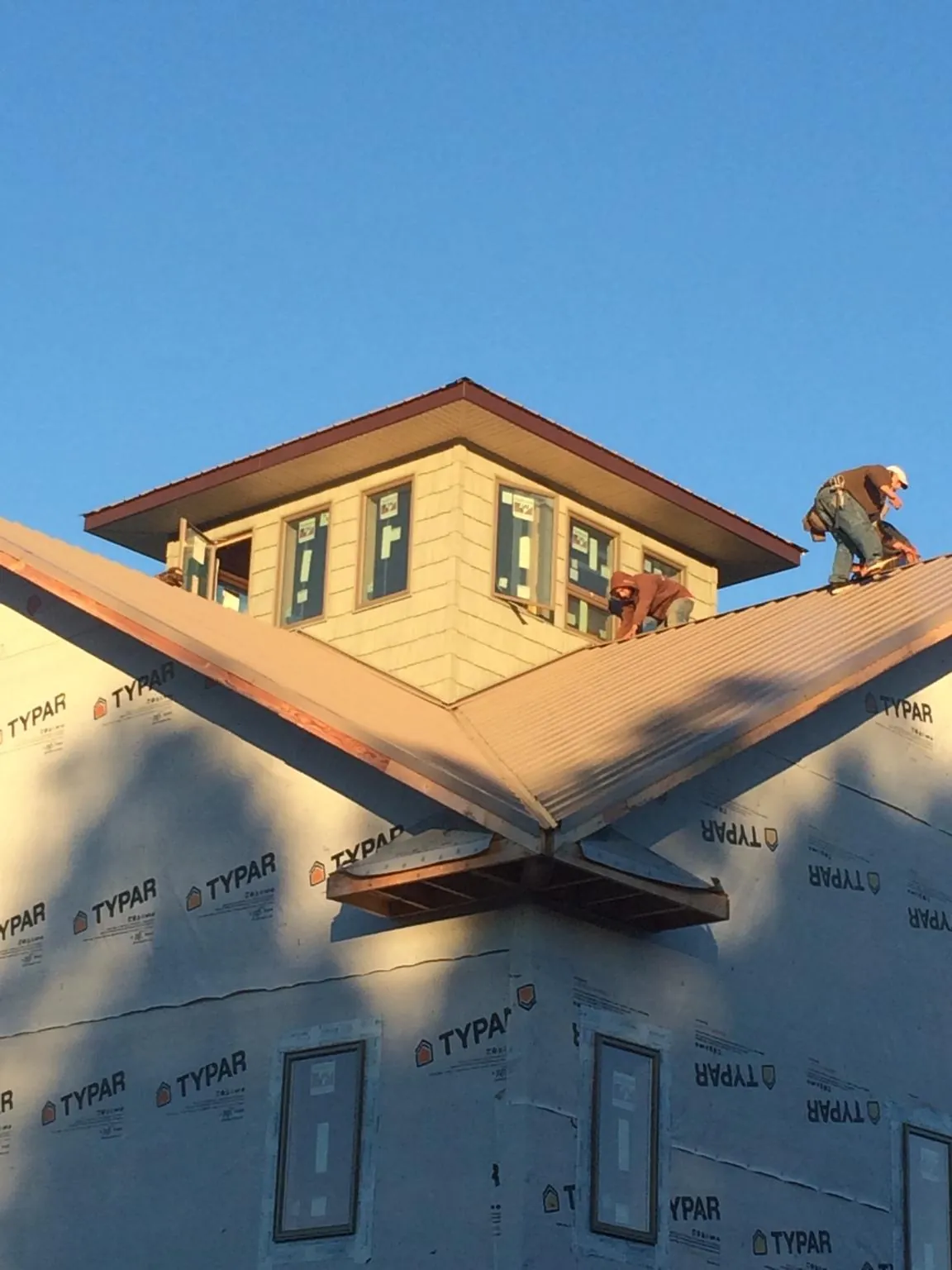 Roofers working around a rooftop cupola on a new metal roof at sunset — Roof Waterproofing in Perley by Roofing Brothers